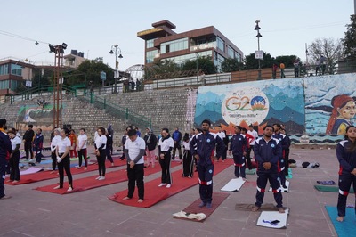 Beach yoga session near Ganga river in Rishikesh with group practicing yoga poses outdoors